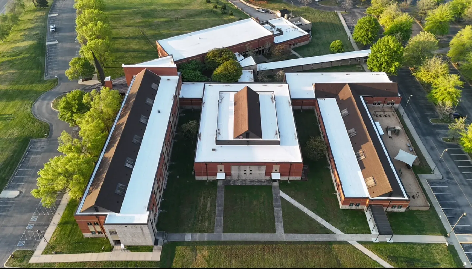 Aerial view of a school campus in Middle Tennessee with a new low-slope TPO roofing system installed by Three Stone