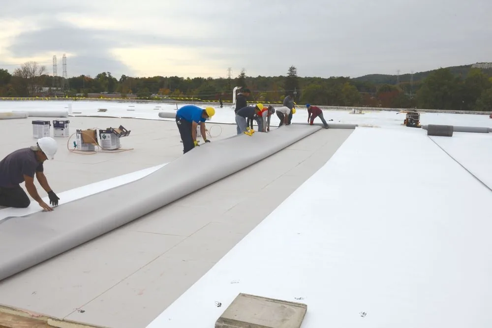 Three Stone crew installing a TPO membrane on a low-slope roof