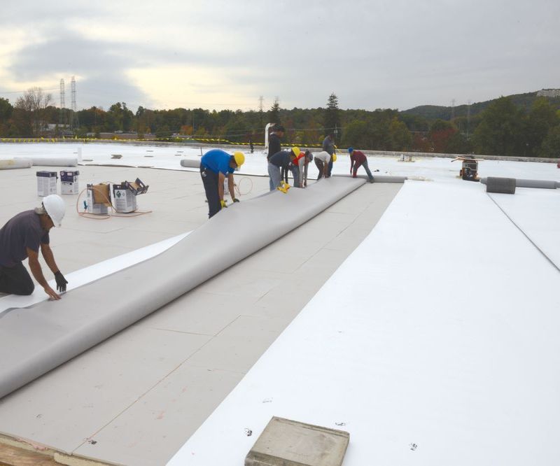 Workers installing new roofing system on a commercial building