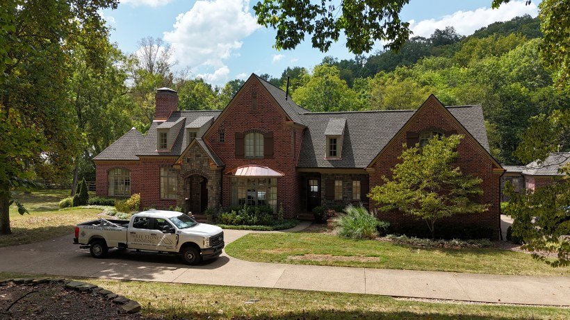 Wide angle view of company truck in front of a residential home with a newly installed asphalt roof