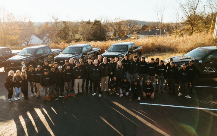 The Three Stone Roofing team standing in front of company vehicles