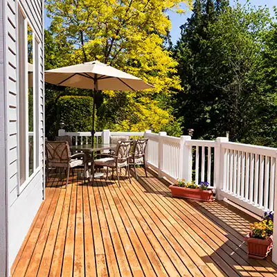 Small wooden deck with white railing and a small seating area