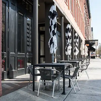 Outdoor seating area with black and white umbrellas at the table that are closed